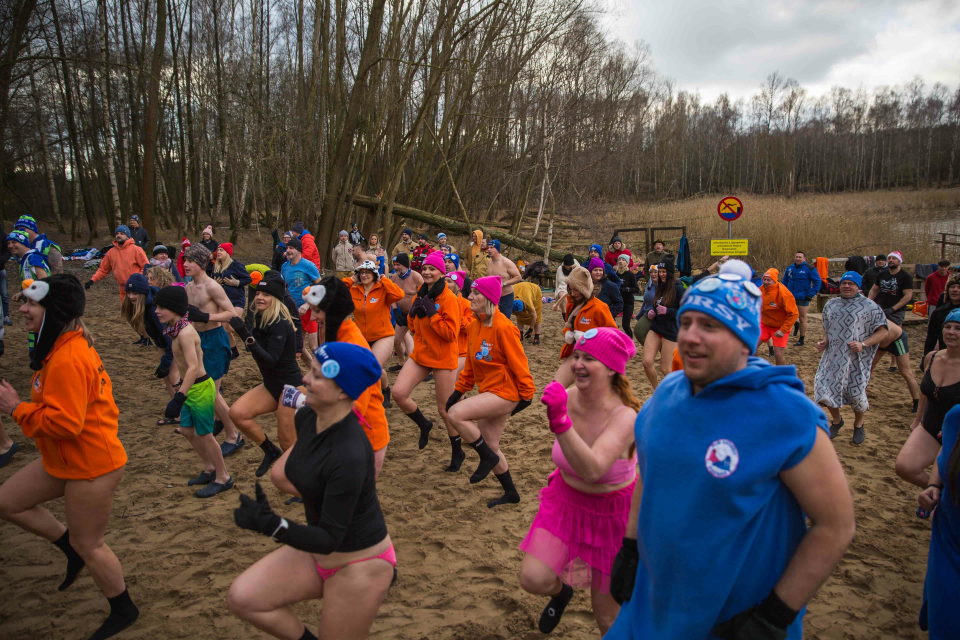 tłum ludzi w strojach kąpielowych robi ćwiczenia na plaży