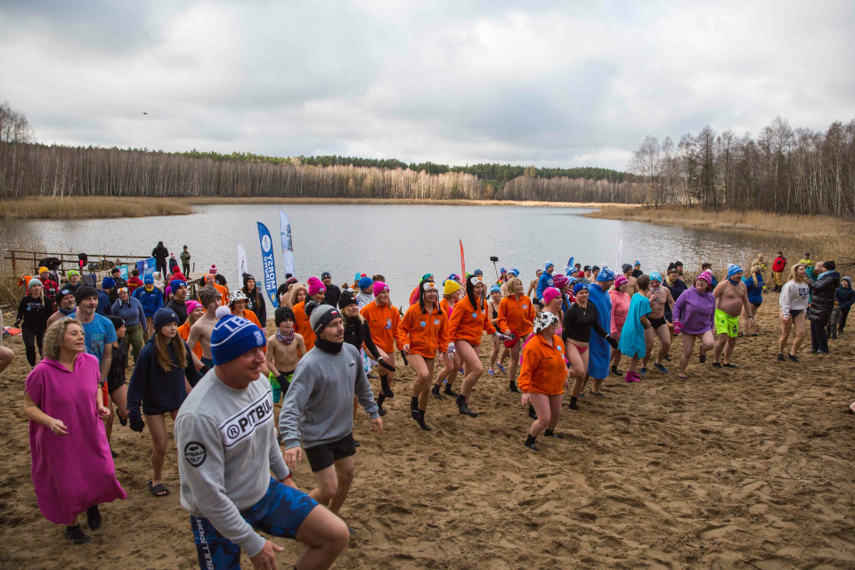 tłum ludzi w strojach kąpielowych robi ćwiczenia na plaży